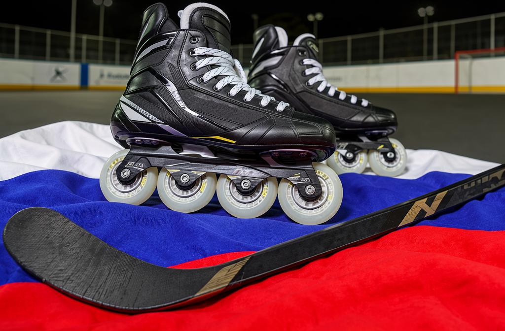 Роликовые коньки и клюшка на фоне флага России на хоккейной площадке